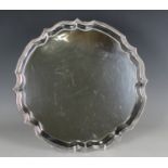 A George V silver circular salver with raised shaped rim, on scroll legs, Sheffield 1915 by James