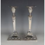 A pair of George III silver Neoclassical candlesticks, each removable square nozzle above an urn