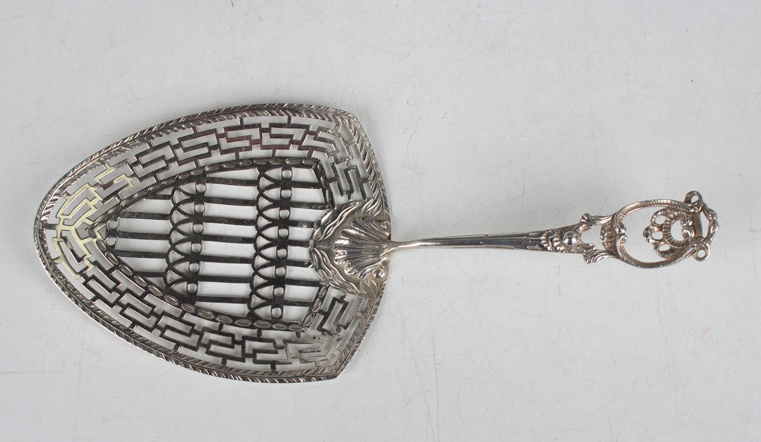 A George III silver fish slice with pierced scroll handle and geometric pierced blade united by a