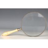 An early 20th century gallery magnifying glass with turned ivory handle, lens diameter 20cm.Buyer’