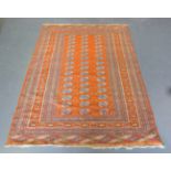 A Pakistan bokhara style rug, mid/late 20th century, the orange field with three columns of guls,