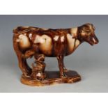 A Staffordshire pottery treacle glazed cow creamer and milkmaid group, early 19th century,