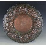 A late 19th century Arts and Crafts copper charger, the wide border repoussé decorated with leaves