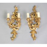 A pair of 20th century Florentine style giltwood two-branch wall lights of foliate carved design,