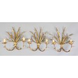 A set of three 20th century gilt metal two-branch wall lights, the backplates shaped as corn