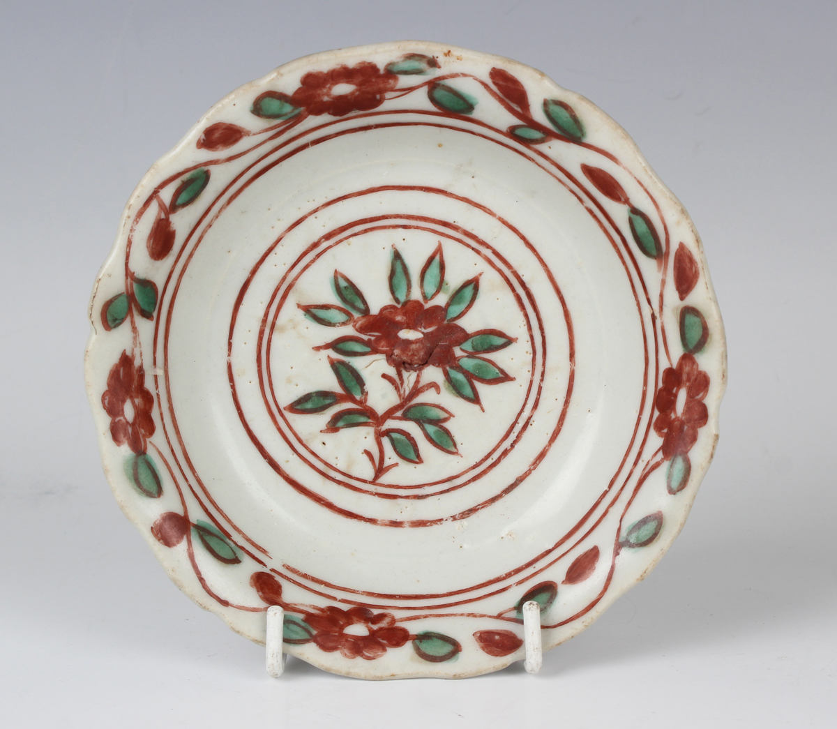 A Chinese wucai saucer dish, Ming dynasty, the centre painted with an iron red and green flower