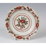 A Chinese wucai saucer dish, Ming dynasty, the centre painted with an iron red and green flower