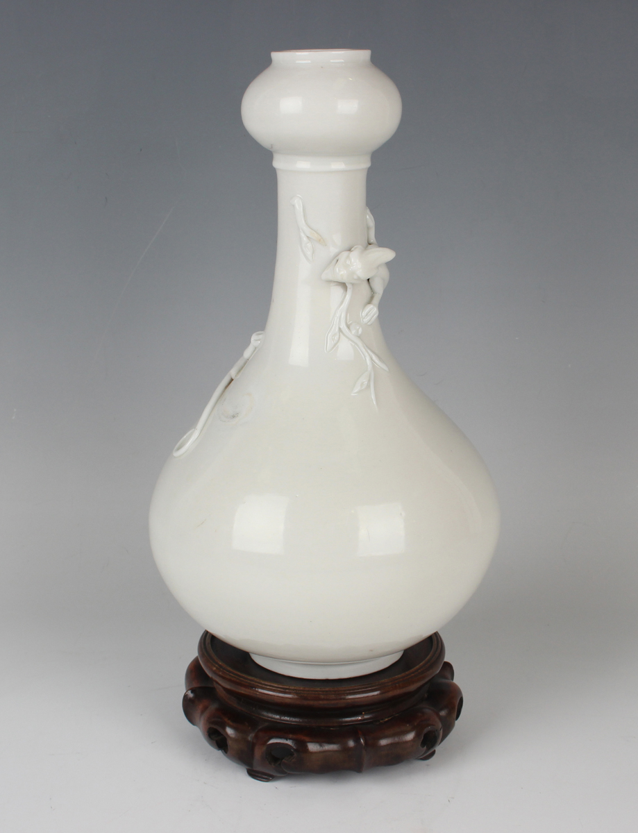 A Chinese blanc-de-Chine porcelain 'chilong' bottle vase, Qing dynasty, the low-bellied body beneath