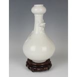 A Chinese blanc-de-Chine porcelain 'chilong' bottle vase, Qing dynasty, the low-bellied body beneath