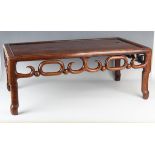 A Chinese hardwood low table, early 20th century, the rectangular panelled top above a carved and