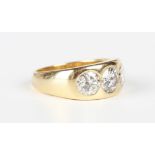 A gold and diamond three stone ring, gypsy set with a row of circular cut diamonds, the principal