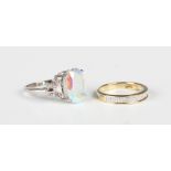 A white gold ring, claw set with a treated oval cut gemstone, with colourless gem set butterfly