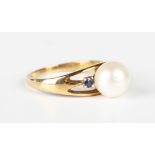 A gold ring, mounted with a cultured pearl between two circular cut sapphires, detailed 'K14',