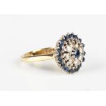 An 18ct gold, sapphire and diamond cluster ring, claw set with a circular cut sapphire within a