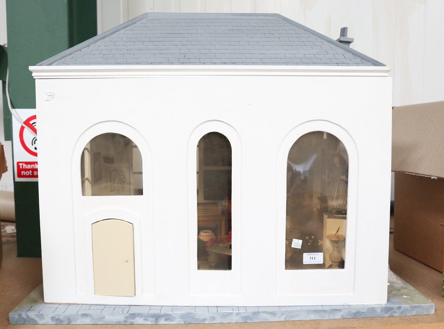 A modern single-storey doll's house/studio with pitched roof, the opening front revealing a room,