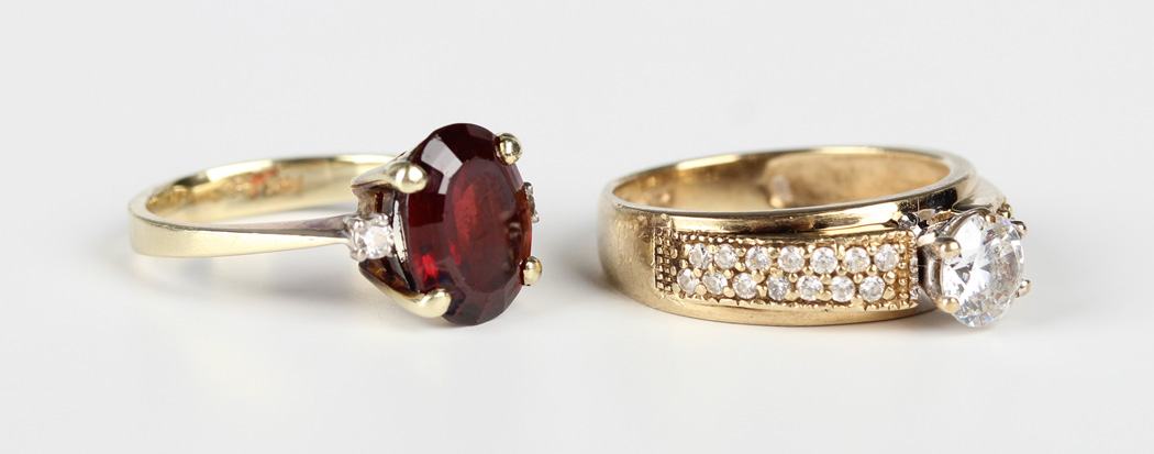 A gold, garnet and diamond three stone ring, claw set with the oval cut garnet between two