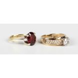 A gold, garnet and diamond three stone ring, claw set with the oval cut garnet between two