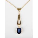 An Art Deco gold and synthetic sapphire single stone pendant necklace, the front in a tapered 'V'