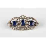 A diamond, sapphire and blue paste set brooch, claw set with an oval cut sapphire between two square