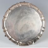 A George V silver circular card salver, presentation inscribed, raised on scroll legs terminating in