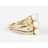 A gold, diamond and cultured pearl ring in a triple shank design, mounted with three cultured pearls