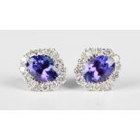 A pair of white gold, tanzanite and diamond cluster earrings, each claw set with the oval cut