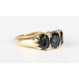 A gold ring, mounted with three oval cut bluish green sapphires with two pairs of circular cut