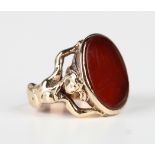 A gold and cornelian ring, mounted with a large oval cornelian, the shoulders cast as figures of