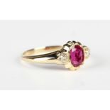 A gold, ruby and diamond ring, mounted with the oval cut ruby between two cushion cut diamonds,