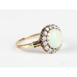 A gold, opal and diamond cluster ring, claw set with the oval opal within a surround of cushion