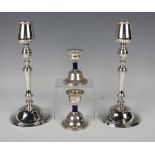 A pair of George V silver candlesticks, each tapering cylindrical sconce on a baluster stem and