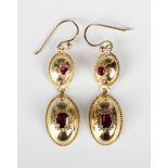 A pair of gold and garnet pendant earrings, each oval drop mounted with a step cut garnet within a