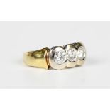 An 18ct two colour gold and diamond ring, mounted with a row of three circular cut diamonds,