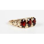 A 9ct gold and garnet three stone ring, claw set with a row of oval cut garnets, London 1992, weight