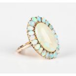 A gold and opal cluster ring, claw set with the principal oval opal within a surround of smaller