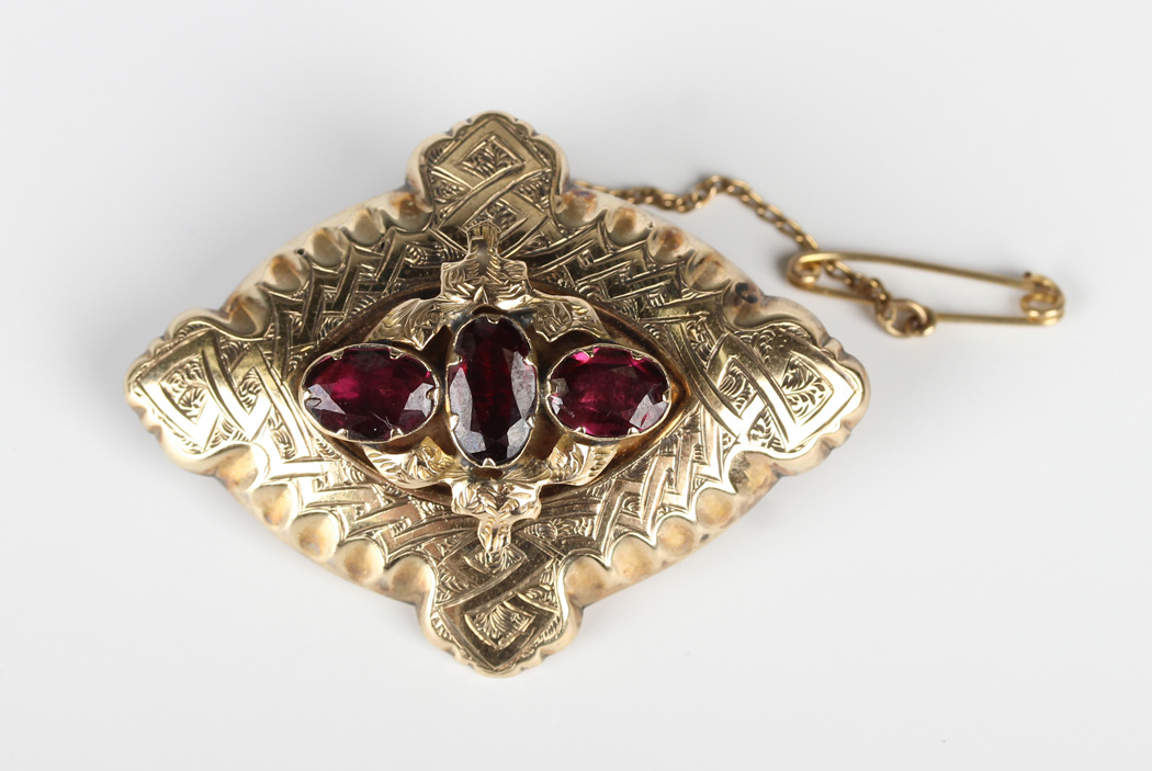 A Victorian garnet brooch, mounted with three oval cut garnets to the centre, otherwise with