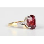 An 18ct gold ring, claw set with an oval cut pink tourmaline between diamond four stone shoulders,