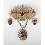 A silver gilt and amethyst brooch in a cannetille work design with three pendant drops, unmarked,