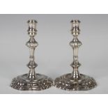 A pair of George II silver tapersticks, each cylindrical sconce above a tapering baluster stem, on a