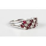 A white gold, ruby and diamond ring in a slanting design, claw set with four rows of circular cut