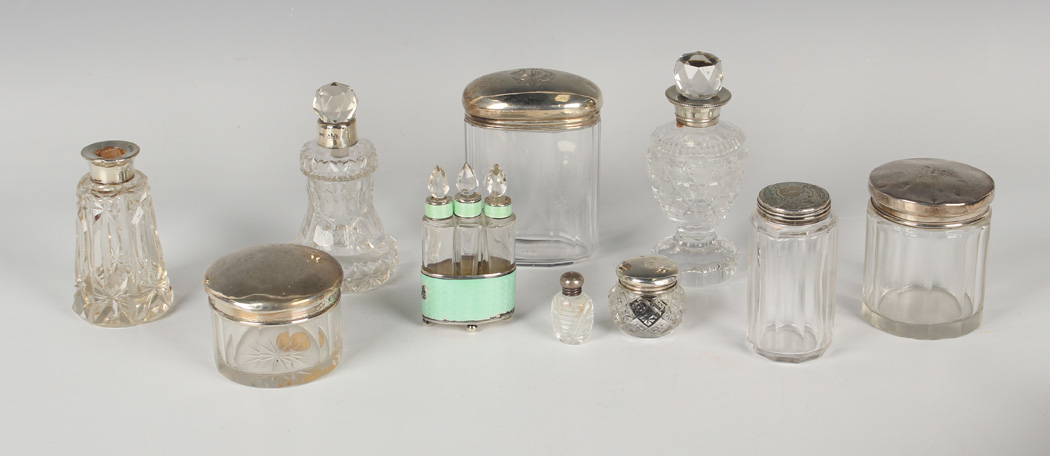 A group of cut glass dressing table bottles and jars with silver lids and collars, a .935 silver and