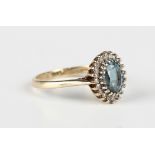 A 9ct gold, blue topaz and diamond oval cluster ring, claw set with the oval cut blue topaz within a