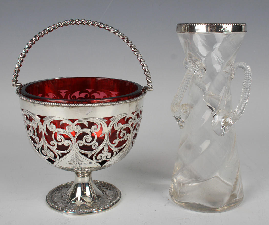 A Victorian silver bonbon basket with spiral swing handle, the circular body pierced and engraved