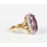 An 18ct gold, amethyst and diamond oval cluster ring, claw set with the oval amethyst within a