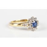 An 18ct gold, sapphire and diamond oval cluster ring, claw set with the oval cut sapphire within a