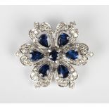 An 18ct white gold, sapphire and diamond brooch in a flowerhead shaped design, claw set with a