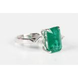 A white gold, emerald and diamond three stone ring, claw set with the large cut cornered rectangular