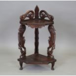 A 20th century Burmese hardwood two-tier corner shelf, the two supports finely carved with beasts