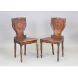 A pair of Regency mahogany hall chairs with carved backs and solid seats, the seat rails stamped '