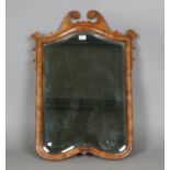 An early 20th century Queen Anne style walnut wall mirror with a shaped swan neck pediment and